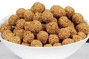 A bowl filled with sesame seed balls, which are traditionally sweetened with jaggery and handcrafted as a snack.